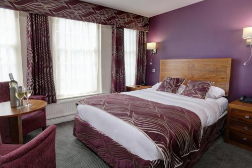 a bedroom with a large bed and purple walls at Best Western Plus Sheffield Mosborough Hall Hotel in Sheffield