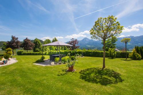 a green yard with a tree and an umbrella at Haus Panorama in Drobollach am Faakersee