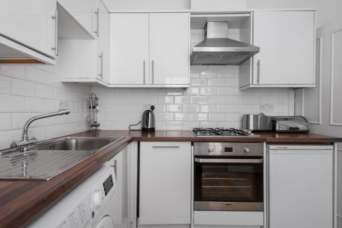 uma cozinha com armários brancos, um lavatório e um fogão em Brighton Brunswick Apartments em Brighton & Hove