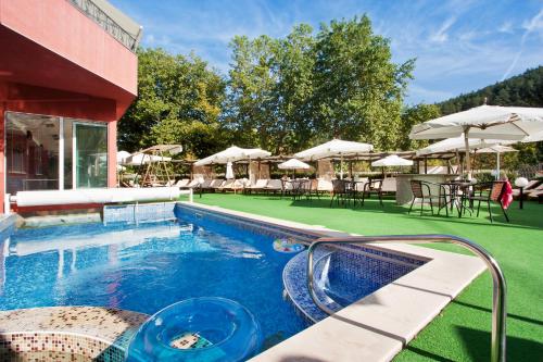 a swimming pool with chairs and umbrellas in a resort at Balneo Complex & Spa Aquatonik in Velingrad