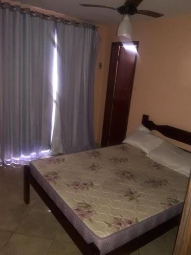 a bedroom with a bed and a window with a bedspread at Edificio caminho do sol in Arraial do Cabo