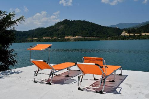 two orange chairs sitting on a dock next to a lake at Keep calm Lake edition in Konjic