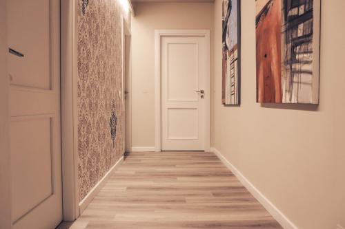 a hallway with a white door and paintings on the walls at B&B Seataly by W Signature Experiences in Civitavecchia