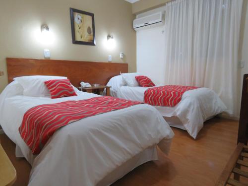 a hotel room with two beds with red and white sheets at Grand Hotel in Reconquista