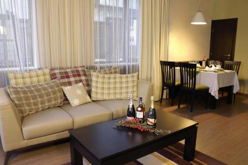 a living room with a couch and a table with bottles of wine at Ruskovets Thermal SPA & Ski Resort in Bansko