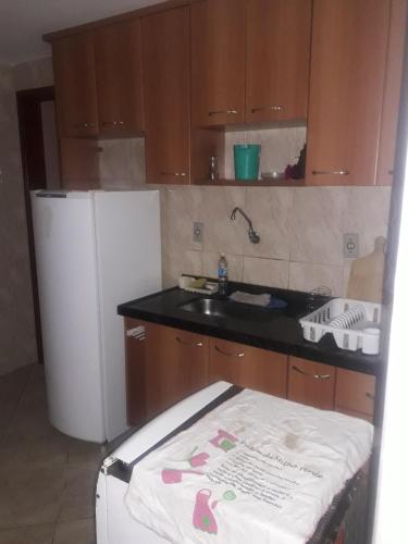 a small kitchen with a sink and a refrigerator at Edificio caminho do sol in Arraial do Cabo