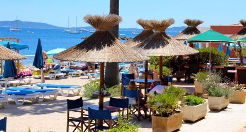 a group of chairs and umbrellas on a beach at Hotel La Potiniere in Hyères