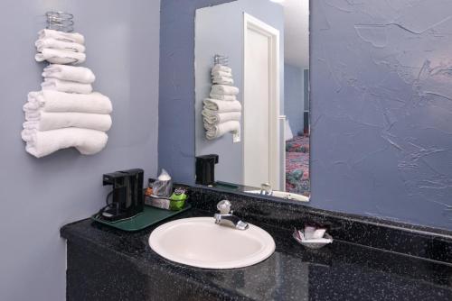 y baño con lavabo, espejo y toallas. en Americas Best Value Inn & Suites, Near The Titanic Museum on 76, en Branson
