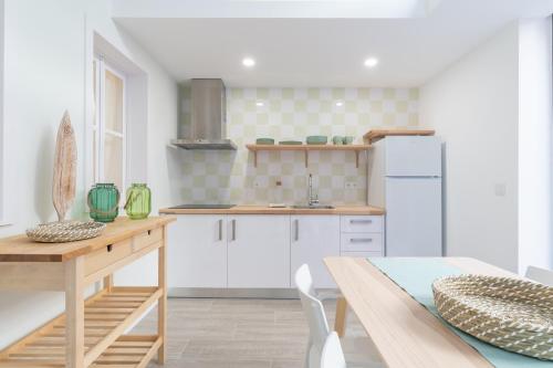 eine Küche mit weißen Schränken und einem Holztisch in der Unterkunft Slowlife Furadouro in Furadouro
