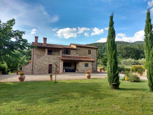 a large stone house with trees in a yard at Casale I Burroni in Arezzo