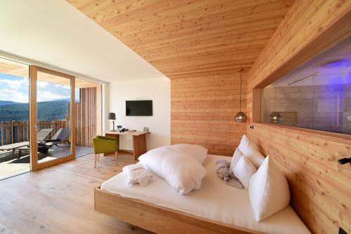a bedroom with a white bed with a wooden wall at Tratterhof Mountain Sky Hotel in Maranza
