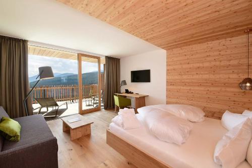 a bedroom with a bed and a desk and a couch at Tratterhof Mountain Sky Hotel in Maranza