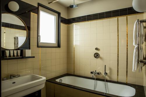a bathroom with a tub and a sink and a mirror at Hôtel du Rond-point des Champs-Élysées - Esprit de France in Paris