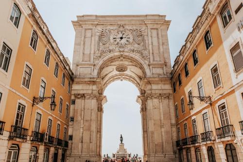 an arch with a clock in the middle of two buildings at TURIM Terreiro do Paço Hotel in Lisbon