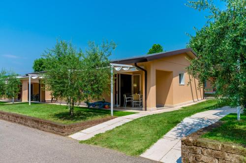 a small house with a porch and trees at Camping Village Du Parc in Lazise