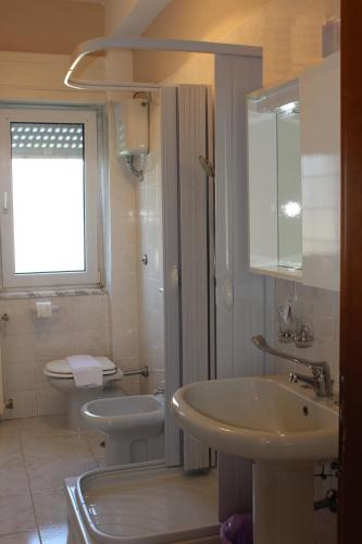 a white bathroom with a sink and a toilet at La Maison in Vallata