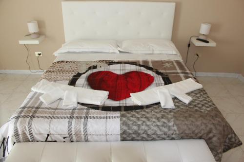 a bed with a red heart pillow on it at La Maison in Vallata