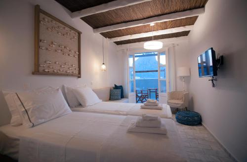 La Playa Boutique Apartments في كاليمنوس: غرفة نوم كبيرة بسريرين ونافذة