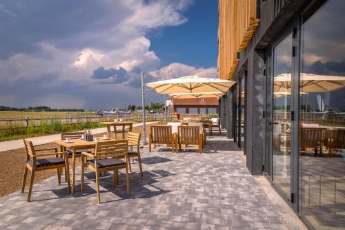 a patio with tables and chairs and umbrellas at Najeti Hôtel Lille Nord in Bondues