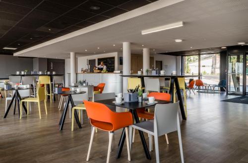 a restaurant with tables and chairs and a bar at Najeti Hôtel Lille Nord in Bondues