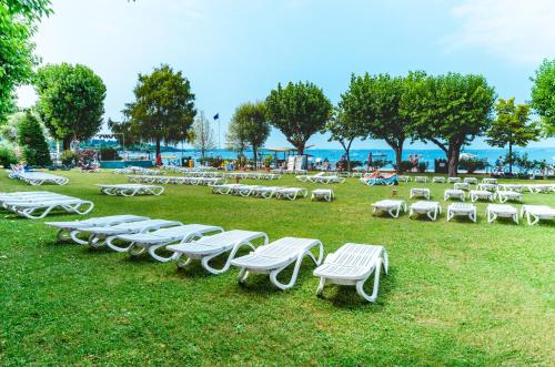 a row of white lounge chairs on the grass at Camping Village Du Parc in Lazise