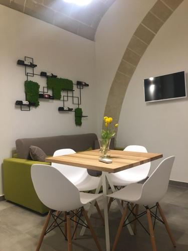 a dining room with a wooden table and white chairs at Egusa73 Favignana in Favignana
