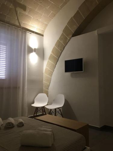 a bedroom with two white chairs and a bed at Egusa73 Favignana in Favignana