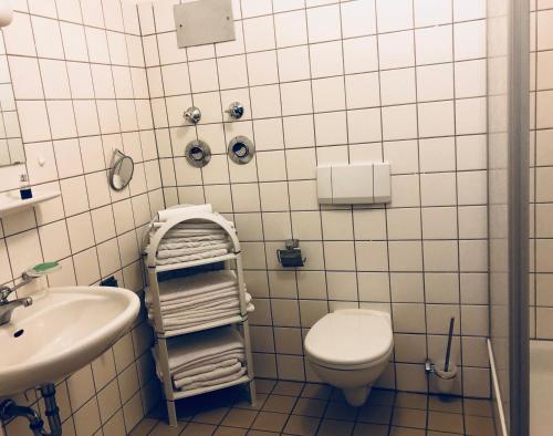 a white tiled bathroom with a toilet and a sink at Ferienwohnung König Max in Bad Alexandersbad