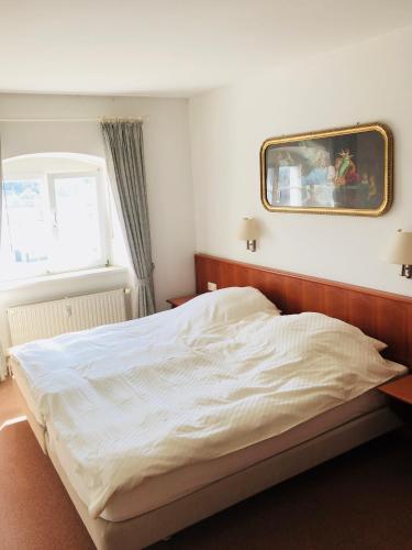 a bedroom with a white bed with a picture on the wall at Ferienwohnung König Max in Bad Alexandersbad