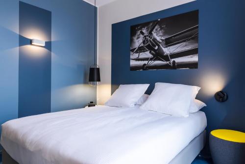 a bedroom with a large white bed with blue walls at Najeti Hôtel Lille Nord in Bondues