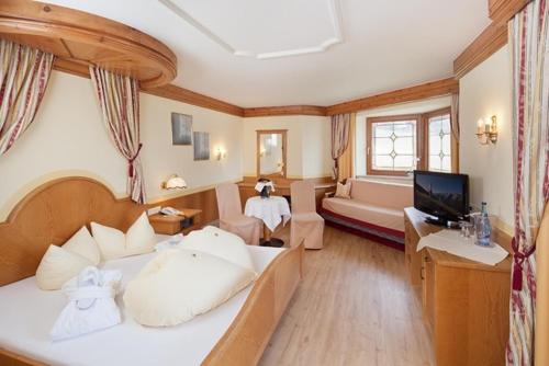 a bedroom with a large bed and a living room at Hotel Magdalena im Zillertal - Urlaub mit Hund in Ried im Zillertal
