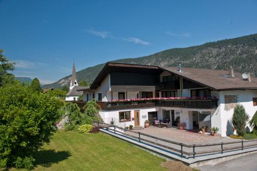 a large white house with a church in the background at Hotel Thaler in Rietz