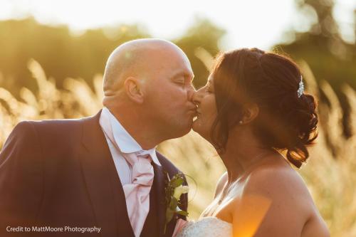 a bride and groom kissing in a field at Twin Oaks Hotel in Chesterfield