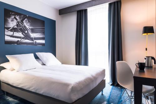a hotel room with a bed and a desk and a window at Najeti Hôtel Lille Nord in Bondues