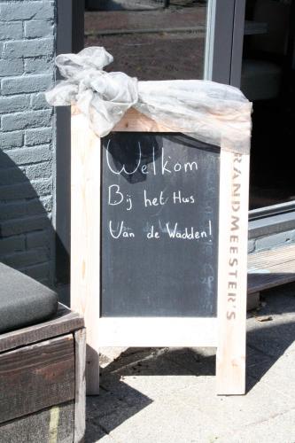 a sign in front of a door with a chalkboard at Het Huis van de Wadden in Den Oever