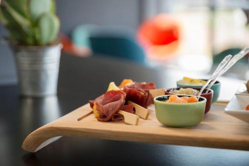 a wooden cutting board with food on a table at Najeti Hôtel Lille Nord in Bondues