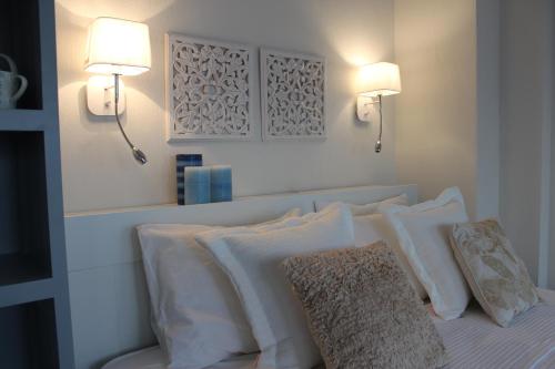 a bed with white pillows and two lights on the wall at Akti Elia Villas Beachfront Chalkidiki in Elia