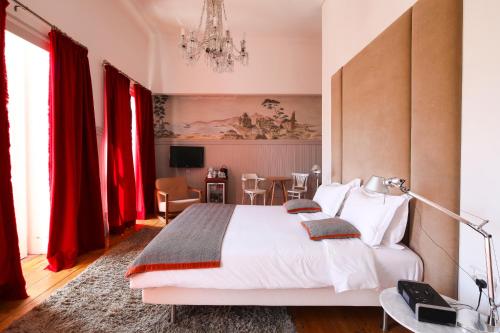 1 dormitorio con 1 cama blanca grande y cortinas rojas en Casa Oliver Boutique B&B - Principe Real, en Lisboa