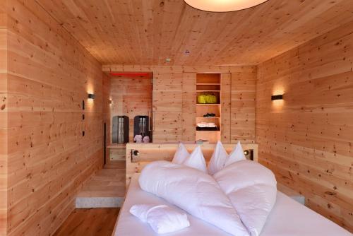 a wooden room with a bed with white pillows at Tratterhof Mountain Sky Hotel in Maranza