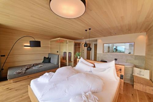 a bedroom with a white bed and a couch at Tratterhof Mountain Sky Hotel in Maranza