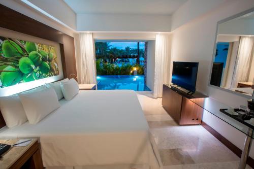a bedroom with a large white bed and a television at Krystal Grand Nuevo Vallarta in Nuevo Vallarta 