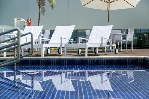 a group of chairs and an umbrella next to a pool at Bugan Recife Boa Viagem Hotel - by Atlantica in Recife