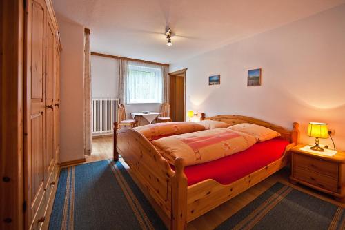 ein Schlafzimmer mit einem Holzbett mit einer roten Decke in der Unterkunft Haus St. Christoph in Mayrhofen