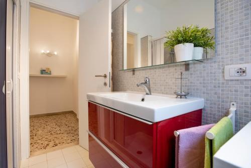 a bathroom with a red sink and a mirror at DELPOSTO Marina di Ragusa (lp) in Marina di Ragusa