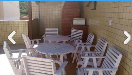 a group of tables and chairs sitting next to a wall at Edificio caminho do sol in Arraial do Cabo