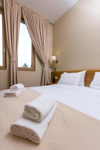a bedroom with a large white bed with towels on it at Hotel Lirak in Tetovo