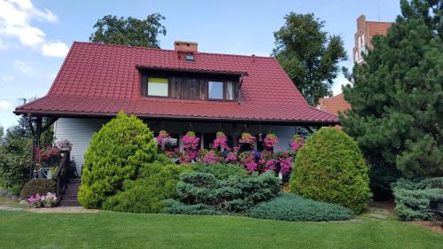 uma casa com um telhado vermelho e alguns arbustos em Dom Gościnny Wejsuny - Mazury em Wejsuny