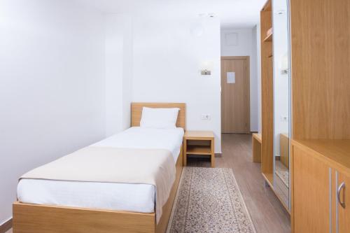 a bedroom with a large white bed and a television at Hotel Lirak in Tetovo