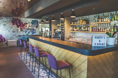 a bar with purple chairs in a restaurant at Hôtel Karène in Saint-Paul-lès-Romans