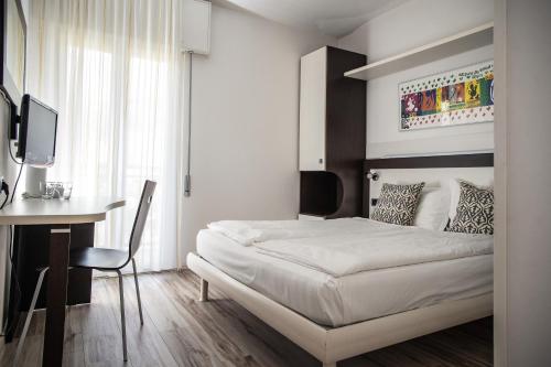 a bedroom with a bed and a desk with a computer at Hotel Villa Alberta in Nago-Torbole